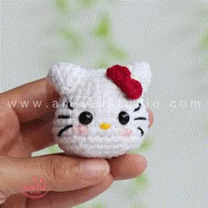 a small crocheted hello kitty with a red bow on it's head