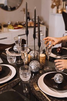 a table set with black and white plates, silverware and wine glasses on it