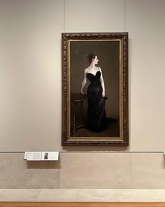 a woman in a black dress standing next to a painting