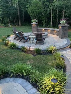 an outdoor patio with chairs and fire pit in the middle, surrounded by landscaping plants