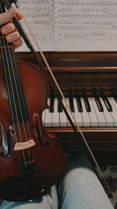 a person sitting in front of a piano and holding a violin