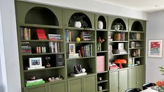 a dining room table and chairs with bookshelves on the wall in front of them