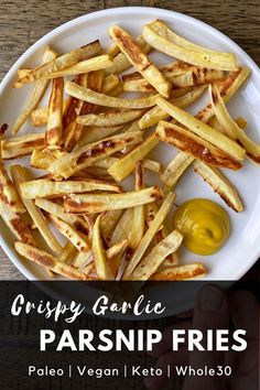 crispy garlic parsnip fries on a white plate with olive dipping sauce