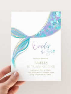 a person holding up a card with an image of a mermaid's tail on it