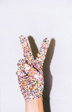 a hand with sprinkles holding up the peace sign