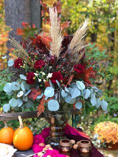 a vase filled with flowers sitting on top of a table next to pumpkins and other decorations