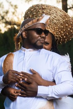 a man and woman dressed in white hugging each other with gold sequins on their hats