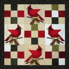 a red bird sitting on top of a green and white checkerboard quilted wall hanging