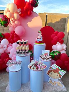 a table topped with lots of cakes and cupcakes next to balloons in the shape of animals