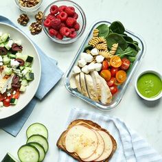 a table topped with plates of food and bowls of fruit next to cucumbers