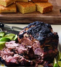 a plate with meat and sliced limes on it next to some cornbreads