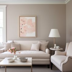 a living room filled with white furniture and a painting on the wall above it's coffee table