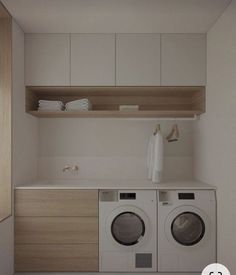 a washer and dryer in a small room with cabinets on the wall behind them