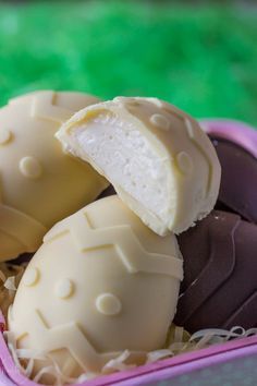 three pieces of white chocolate in a pink container on a green tableclothed surface