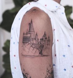 a man's arm with a castle tattoo on it and stars in the background