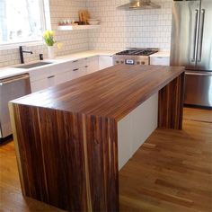 a large kitchen island in the middle of a hardwood floored area with stainless steel appliances