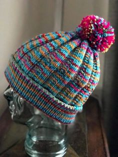 a knitted hat on top of a glass head