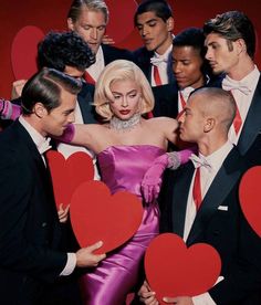 a group of men and women in tuxedos holding heart shaped paper cut outs