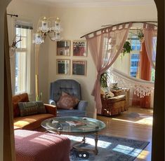 a living room filled with furniture and a chandelier above a glass top table