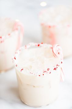 three glasses filled with white liquid and candy canes