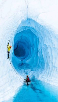 two people in kayaks are inside an ice cave that is blue and has snow on it