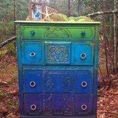 a multicolored dresser in the woods with an ornate design on it's drawers