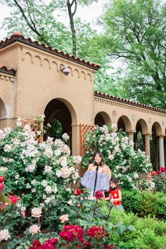 a woman and child standing in front of some flowers