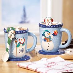 two mugs with snowmen on them are sitting on a table next to each other