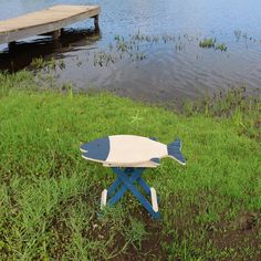 a small blue and white table sitting on top of a grass covered field next to a body of water