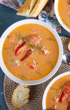 three bowls of lobster soup with bread on the side