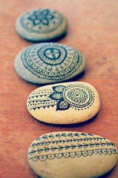 three painted rocks sitting on top of a wooden table next to each other with designs on them