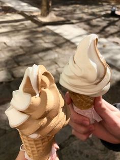 two people holding ice cream cones in their hands