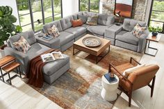 a living room filled with lots of furniture next to a fire place and large windows