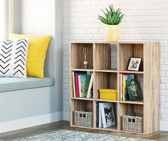 a living room with a couch, window and bookshelf on the floor in front of a white brick wall