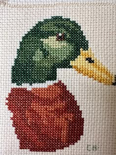 a close up of a cross stitch pattern on a pillow with a duck and pumpkin