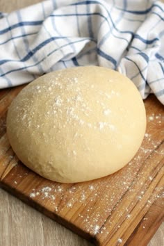 a ball of bread sitting on top of a wooden cutting board next to a blue and white towel