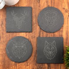 three coasters with designs on them sitting on a wooden table next to a cup