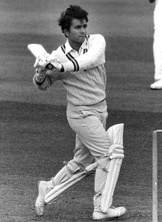 a man swinging a cricket bat on top of a field