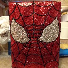 a red and silver spiderman canister with sequins on it's face