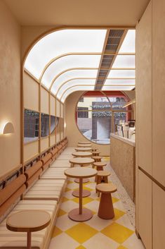 an empty restaurant with tables and benches lined up against the wall, in front of a circular window