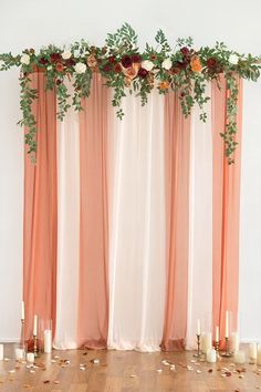 an arrangement of flowers and greenery decorates the top of a curtained backdrop