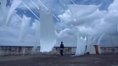 there is a man standing in front of some kites that are blowing in the wind