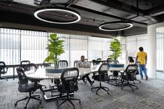 two men are standing in an office with tables and chairs