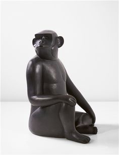 a statue of a monkey sitting on the ground with its legs crossed and eyes closed