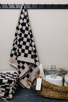 black and white checkered towel hanging on the wall next to a basket with cotton balls