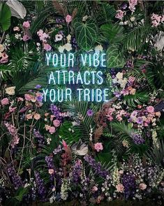 the words your vibe attracts your tribe surrounded by flowers and leaves on a green wall