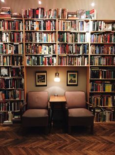 two chairs sitting in front of a book shelf filled with books