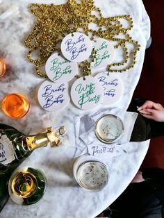 the table is set up with wine glasses, bottles and confetti on it