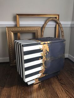 a black and white striped box sitting on top of a wooden floor next to two framed pictures