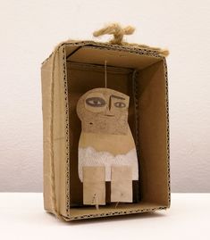 an origami doll in a cardboard box